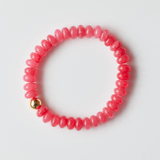Pink beaded bracelet with a gold bead on a white background