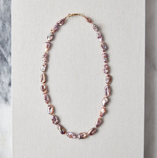 Pearl necklace on a white card with a marble background