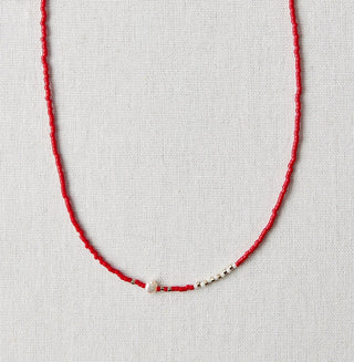 Red necklace on a white card with a marble background