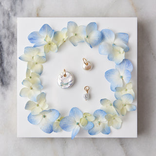 Set of pearl charms displayed on a decorative card with blue and white flowers on a marble surface