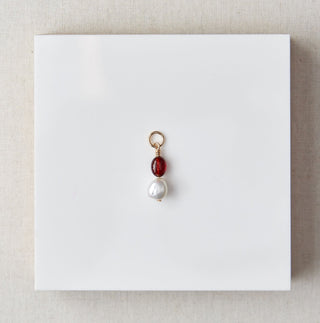 Pearl pendant  set on a white card with beige box on marble surface