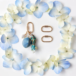Jewelry set with Charms and a ring on a white card with blue and white flowers, placed on a marble surface.