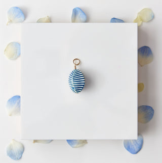 Blue striped charm on a white card with blue polka dots on a marble surface