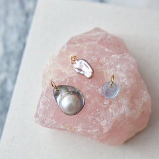 Three earrings displayed on a pink crystal with a blurred background