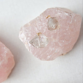 Pearl earrings on pink stone with a white background