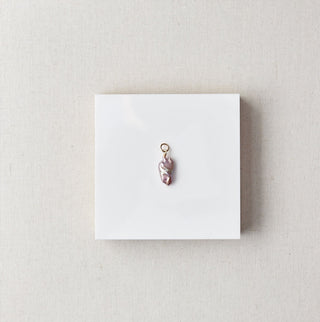 Jewelry pendant on a white card with a beige box on a marble surface