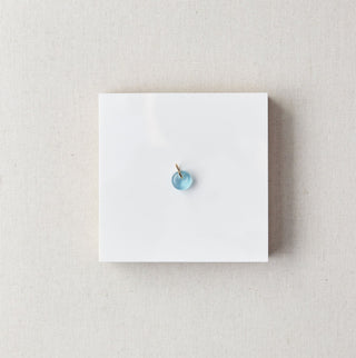 Small blue gemstone on a white card with a marble background