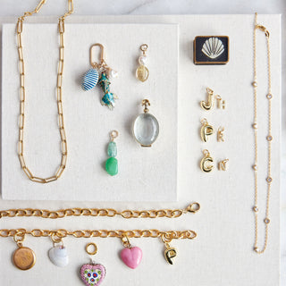 Collection of necklaces and charm pendants on a white card with a marble background