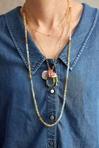 Long beaded necklace with floral charm on a blue denim shirt