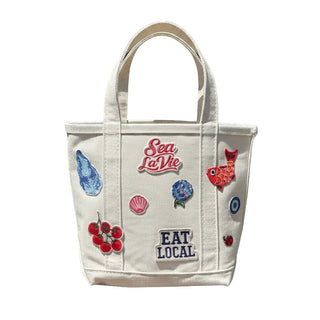 White tote bag with colorful patches and text on a white background