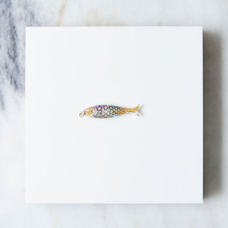 Decorative blue fish pendant on a white card with a marble background