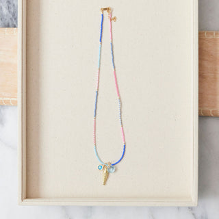 Necklace with shell charms displayed in a wooden box on a marble surface