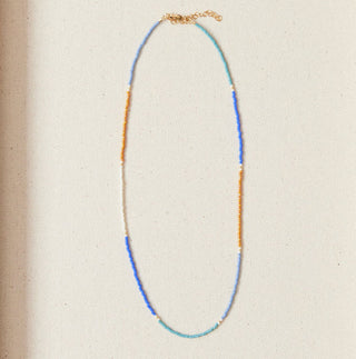 Necklace displayed in a wooden box with seashells on a marble background