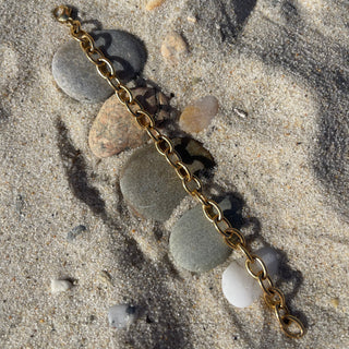 Gold chain bracelet with sea glass pendants on a sandy surface