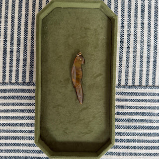 Decorative parrot pendant on a green tray with a striped fabric background