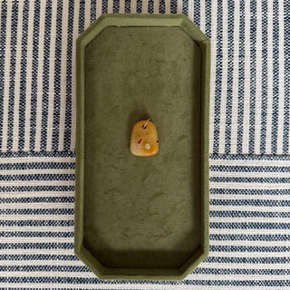 Small stone on a green tray with a striped fabric background