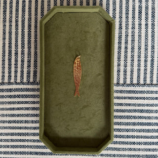Green tray with a fish pendant on a striped fabric background