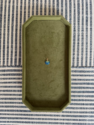 Green jewelry box with a blue gemstone on a striped fabric background