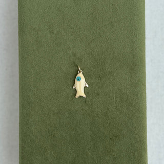 A small gold fish-shaped pendant with a blue stone accent, displayed on top of an olive green velvet jewelry box against a light gray background.