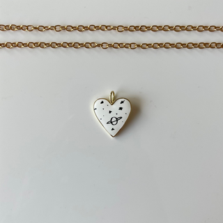 Heart-shaped pendant necklace on a white card with a marble background