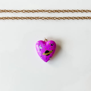 Necklace with a heart-shaped pink pendant on a white card against a marble background