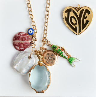Necklace with various charms on a white card with love branding, placed on a marble surface.
