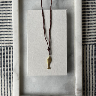 Necklace with a fish pendant on a white card inside a decorative frame.
