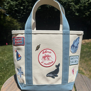 Canvas tote bag with embroidered patches on a wooden surface outdoors
