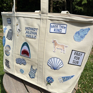 Beige tote bag with various patches on a wooden stool outdoors