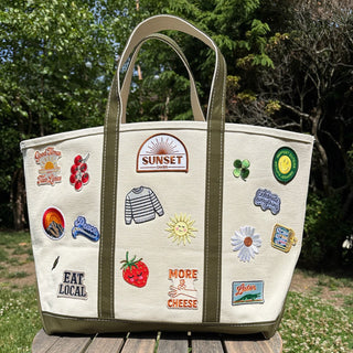 Tote bag with various stickers on a wooden stool outdoors