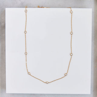 Gold necklace with cz on a white card with a marble background