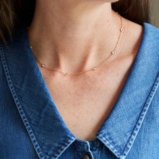 Person wearing a gold necklace with a blue denim shirt