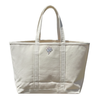Beige tote bag with a small  flower patch on a white background