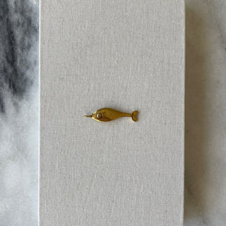 Brass fish charm on linen