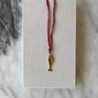 brass fish on dark pink silk on linen background