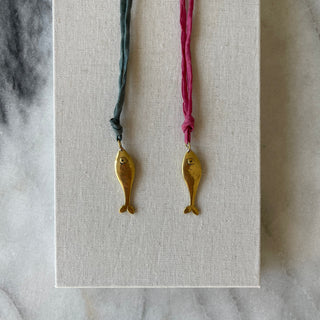 brass fish on silk on linen background