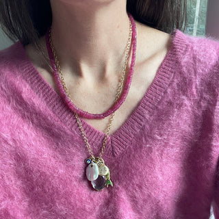 Person wearing a pink sweater and gold necklace with a pendant.