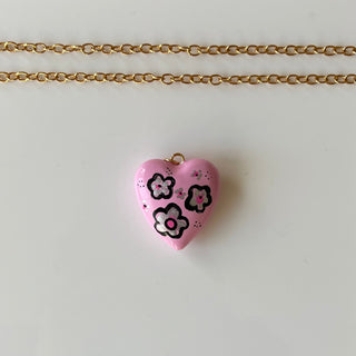 handprinted pink heart pendant on a white surface